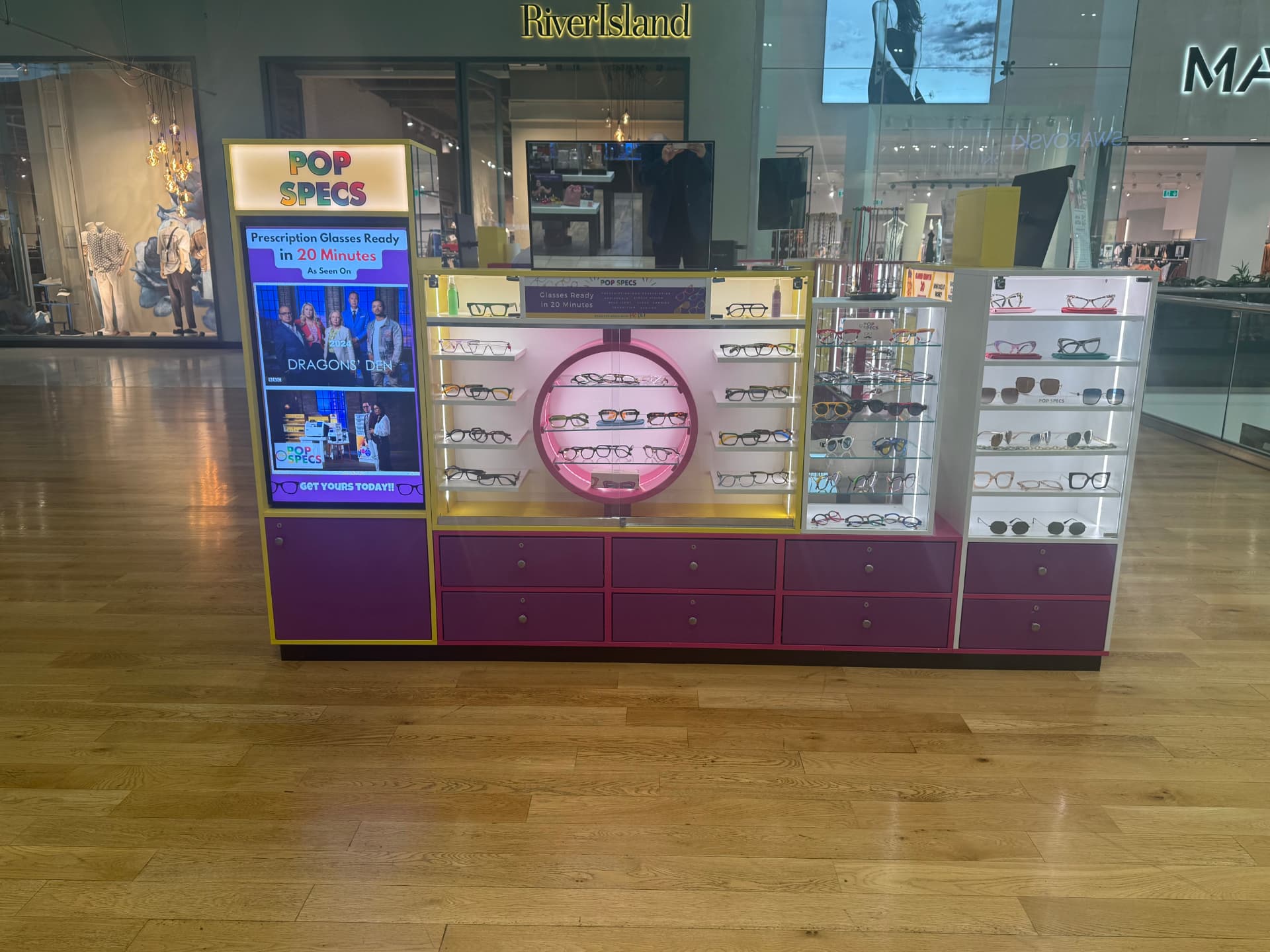 The Pop Specs kiosk at Derbion in Derby, with lit displays of prescription glasses frames outside River Island